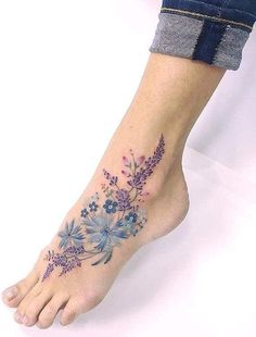 a woman's foot with blue and purple flowers on the bottom of her leg