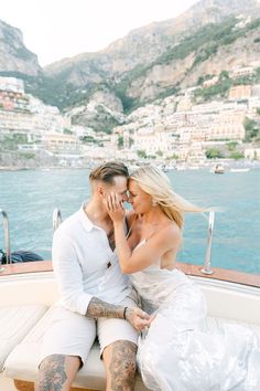 a man and woman sitting on the back of a boat in front of a body of water