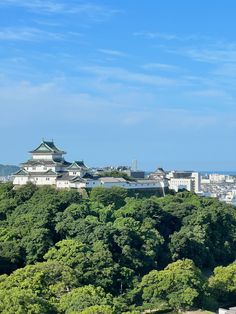 the city is surrounded by many trees and buildings on top of it, with a blue sky in the background