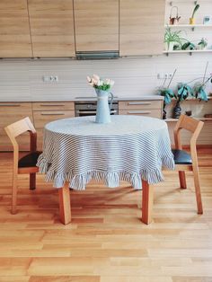 a kitchen table with a blue and white checkered cloth on it, surrounded by wooden chairs