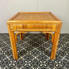 a bamboo table on a tiled floor with black and white tiles in the back ground