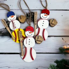 snowman ornament with baseballs and mitts hanging from strings on white wooden background