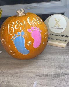 a painted pumpkin sitting on top of a wooden table next to a book and pencils