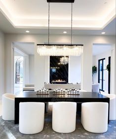 an elegant dining room with white chairs and chandelier