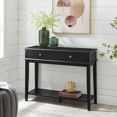 a black console table with two drawers and a plant on top in a white room