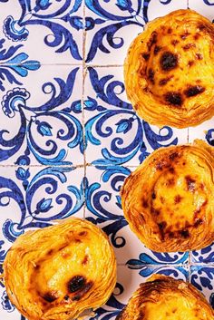 three baked pastries sitting on top of a blue and white tile