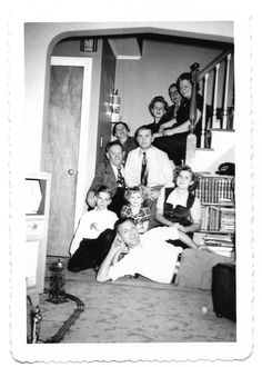 black and white photograph of people sitting on the floor in front of stairs with their arms around each other