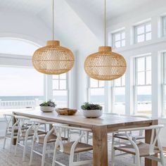 a dining room table and chairs in front of large windows with an ocean view behind them