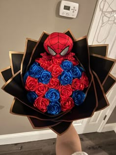 a person holding a bouquet of roses with a spider - man face on it's head