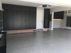 an empty garage with black cabinets and white doors on either side of the garage door