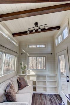 the interior of a tiny house with wood floors and white walls, built in shelving units