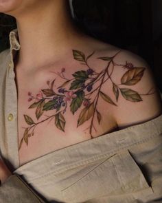 a woman's chest with flowers and leaves painted on her chest, while she is looking at the camera