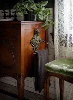 a green chair sitting in front of a wooden cabinet next to a potted plant