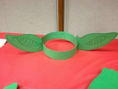 a paper plate sitting on top of a bed with two green leaves cut out of it