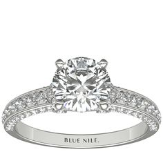 a white gold engagement ring with diamonds on the band and a round brilliant cut center stone