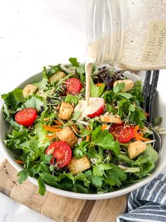 a salad with dressing being poured into it