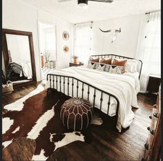 a bed sitting on top of a hard wood floor next to a white and brown rug