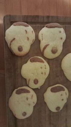 some cookies are on a wooden board and have chocolate chips in the shape of teddy bears