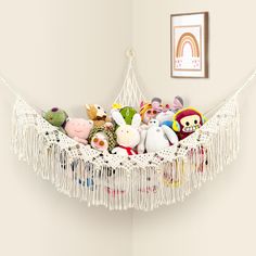 a hammock filled with stuffed animals on top of a white floor next to a wall