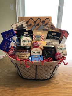 a wine and cheese gift basket is displayed on a wooden table with purple ribbon around it