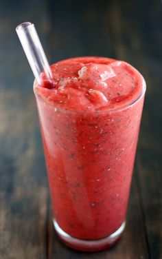 a smoothie in a tall glass with a straw sticking out of it's side