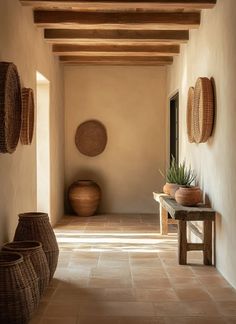 the hallway is lined with wicker baskets and potted plants, along with two benches