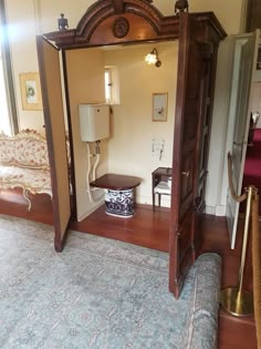 an open doorway leading into a bedroom with a couch and chair in it, next to a mirror