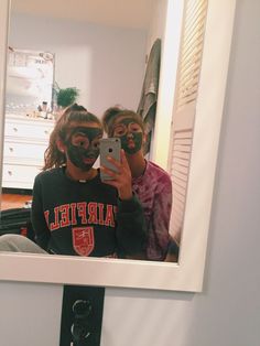 two people with face paint are taking a selfie in the reflection of a mirror