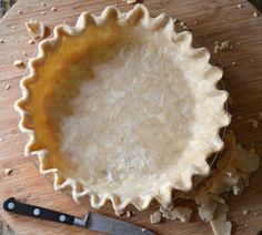 an uncooked pie sitting on top of a wooden cutting board next to a knife