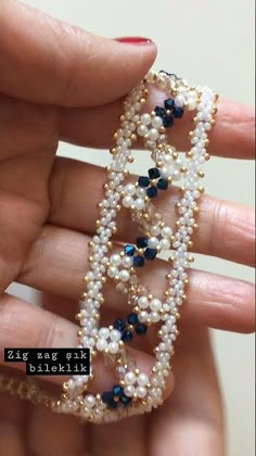 a hand holding a beaded bracelet with pearls and blue beads on it's sides