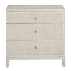 a white dresser with three drawers and gold knobs on the bottom drawer, against a white background