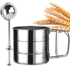 a large metal container with a spoon next to it and some ears of wheat in the background