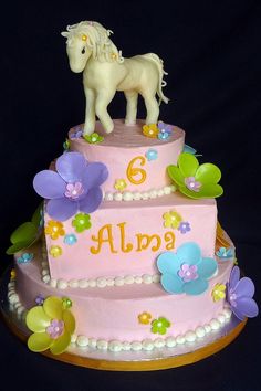 a three tiered cake decorated with flowers and a horse figurine on top