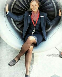 a woman is sitting in front of an airplane engine with her arms out and legs crossed