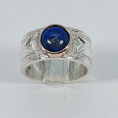 This elegant, Lapis Lazuli Ring has been carefully handcrafted in 925 Sterling Silver, 10k Yellow Gold and authentic Lapis Lazuli.  This impressive ring is great for any occasion! buy it for someone special or buy it for your-self! Upon request a personalized message can be added to the inside of the ring.   Ring is size 7 1/2  but it can be resized at no extra cost and it will be shipped to you in an elegant gift box. Ring weights 10.2 grams Ring Band is :10.0 mm Once ring has been shipped a tr Heirloom Style Blue Jewelry With Polished Finish, Heirloom Blue Jewelry With Polished Finish, Blue Heirloom Jewelry With Polished Finish, Artisan Hallmarked Engraved Ring For Anniversary, Artisan Oval Engraved Ring For Anniversary, Artisan Hallmarked Rings For Anniversary, Artisan Engraved Oval Ring For Anniversary, Artisan Blue Ring Stamped 925, Blue Engraved Sterling Silver Rings