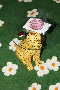 a glass table topped with a leopard figurine next to a pink candle holder