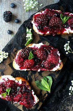 three pieces of bread with berries and whipped cream on them, sitting on a table