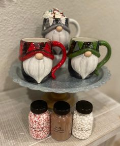 three christmas mugs sitting on top of a glass shelf next to spices and pepper shakers