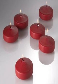 five red floating candles on a white surface