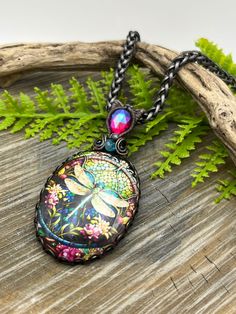 a necklace with an image of a dragon and flowers on it sitting on a piece of wood