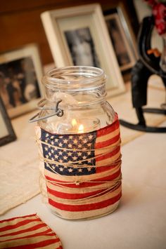 a mason jar with an american flag on it and some pictures in the back ground