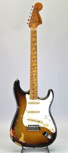 an electric guitar sitting on top of a metal stand in front of a white background