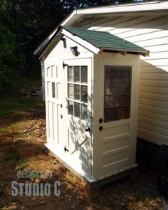 a small white shed with a green roof