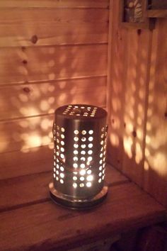 a lit candle sitting on top of a wooden table next to a wall with wood slats