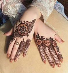 a woman's hands with henna tattoos on her arm and hand, both decorated with flowers