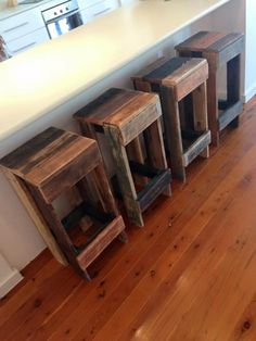 three wooden stools sitting on top of a hard wood floor next to a counter