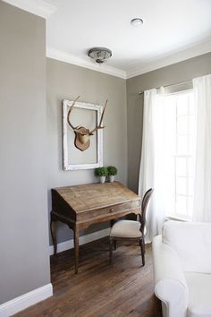 a living room with a couch, table and deer head on the wall