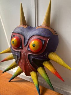 an odd looking mask with spikes on it's head and two large yellow horns