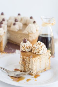 a piece of cake on a white plate with a fork next to it and a glass pitcher