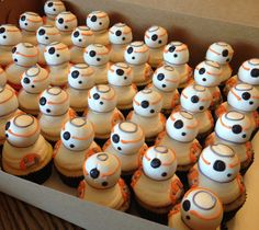 a box filled with lots of cupcakes covered in white frosting and orange icing